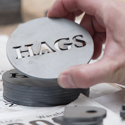 Close up of a HAGS label made with steel which gets attached to products.